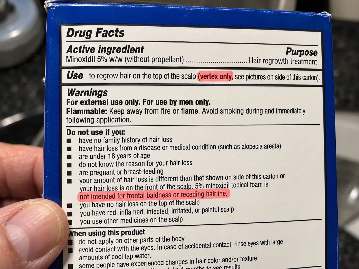 Close-up of the Drug Facts panel on a minoxidil foam can, with the line 'Not intended for frontal baldness or receding hairline' highlighted