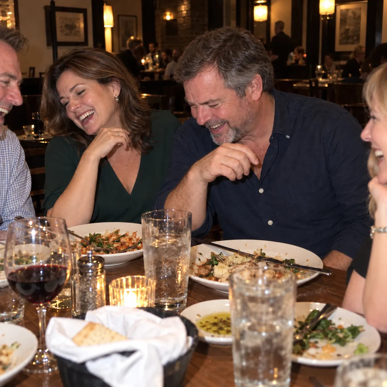 A man laughing at dinner with his wife and friends